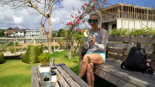 Young, Happy Woman Drinking Cocktail Sitting in Garden Cafe 20s