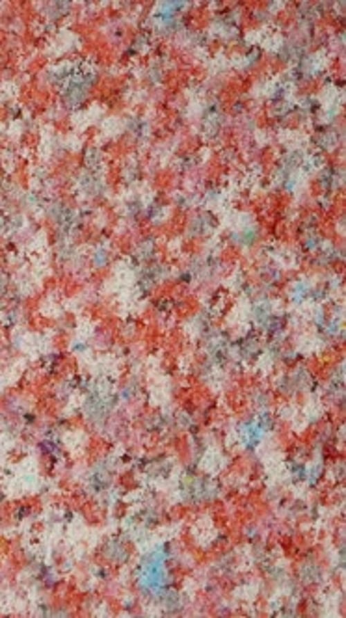 Vertikal. Schaumiges, weiches Material aus recycelten Abfällen. Rote, weiße und blaue Sprenkel
.