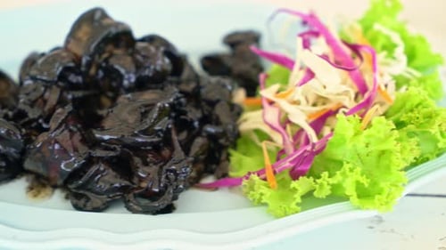 Cooked Black Squid Dish Served With Cabbage