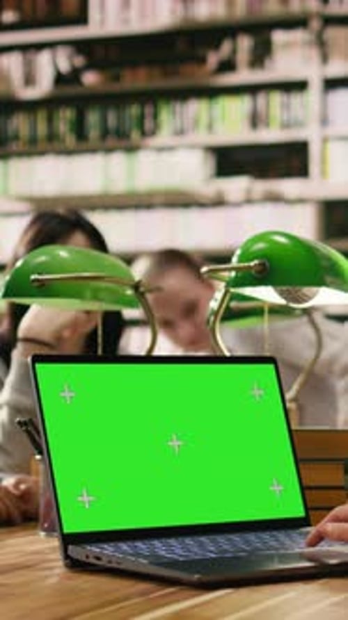 Vertical Video Green Screen Mockup on Laptop with Peers at Wooden Library Desk