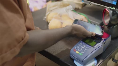 Man Paying with Smartphone at Food Store