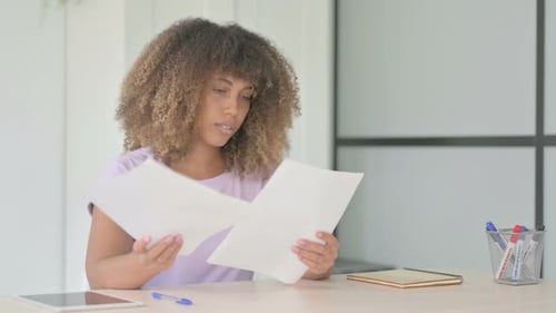 Woman Celebrates Success Reading Documents at Desk