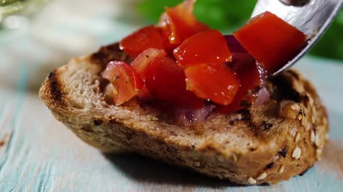 Adding Tomatoes to Bruschetta in a Home Setting