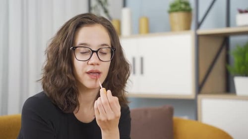 Beautiful woman applying lipstick, gloss.