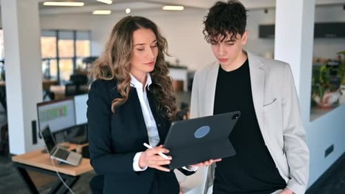 Business session in an office. Woman and a young man discussing business affairs, tablet. Slow motio