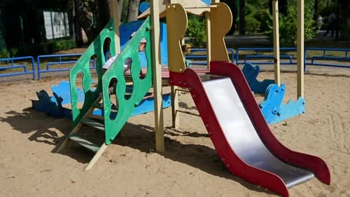 Male toddler goes up slowly by the slide on the playground.