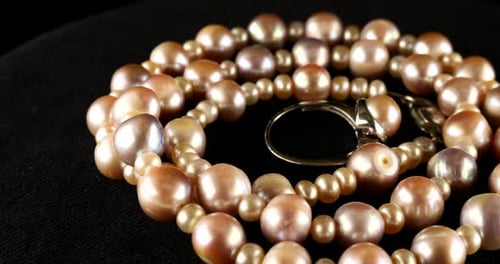 Necklace and silver ring made of natural sea pearls on black velvet.