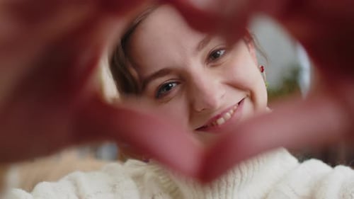Woman Makes Heart with Hands in Close Up