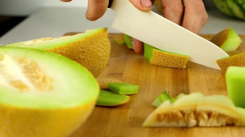 Trancher le melon Galia en morceaux à l'aide d'un couteau en céramique sur une planche à découper en bambou