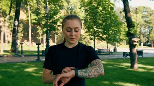 Athletic Woman Checking Smartwatch in Park