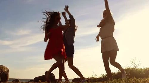 Three Women Dancing at Sunset Near the Sea
