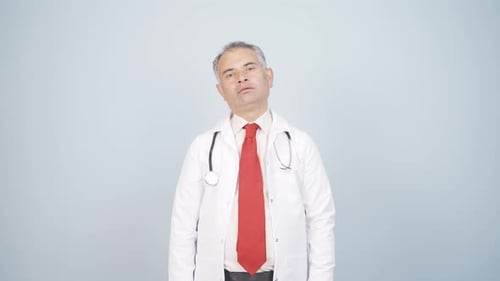 The doctor looks at the camera with a plain expression.