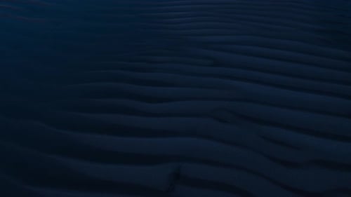Aerial, sand dune ridge patterns on dark night