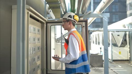 Engineer Pushes Buttons on Electrical Panel with Tablet