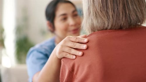 Caring Nurse Comforts Senior Adult in Home Setting