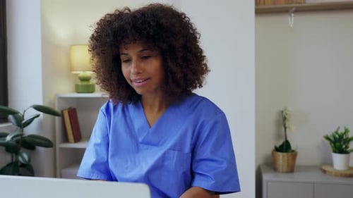 Young Female Nurse Working on Laptop Computer at Home Office Workplace