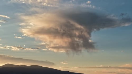Timelapse estático de uma nuvem de chuva solitária brilhando com as cores do pôr do sol