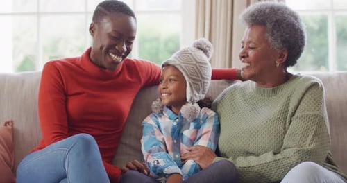 Video portrait of smiling african american mother, daughter and grandmother sitting in living room