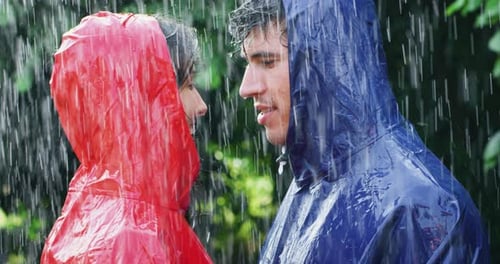 Affectionate Couple Wearing Raincoats Embracing in the Rain