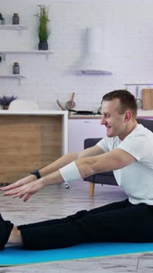 Man Stretching Legs on Exercise Mat Indoors