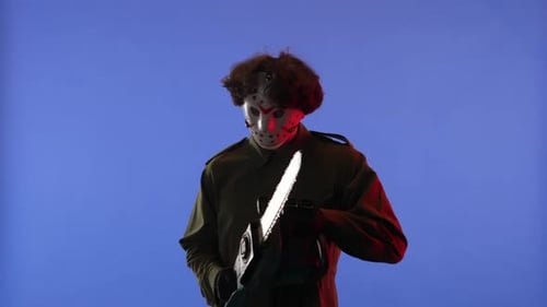 Man in White Mask with Chainsaw in Hands on Blue Background with Red Neon Light Image of Jason