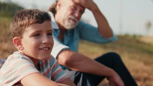 Boy and Grandfather Relaxing in a Sunny Field