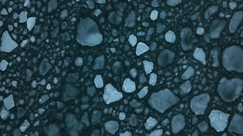 Large ice floes gently moving in the waves of the sea. Top down lifting and rotating shot