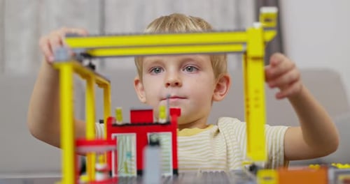 Child Boy Playing and Building with Colorful Plastic Bricks at the Table