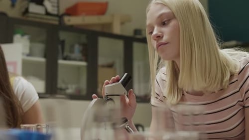 Junior high student conducts scientific experiment with microscope in classroom