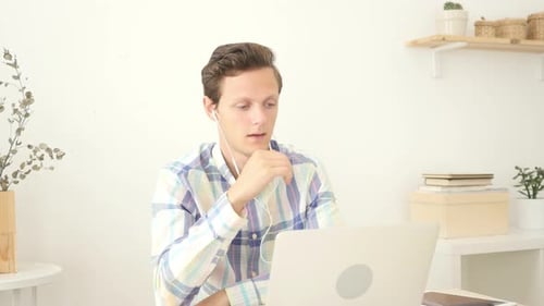 Young Adult Using Laptop for Video Call at Desk