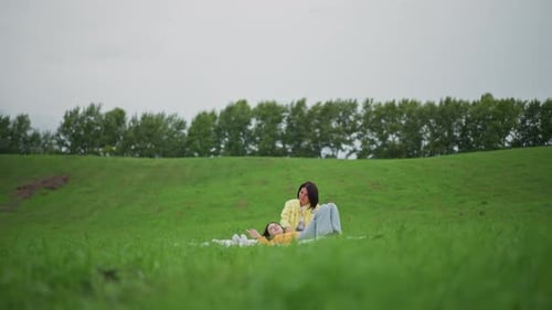 Mother and Child Relaxing on Blanket in Green Field