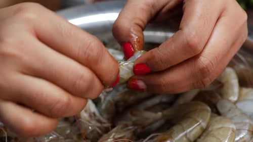 Hands Peeling Raw Shrimp in Bowl