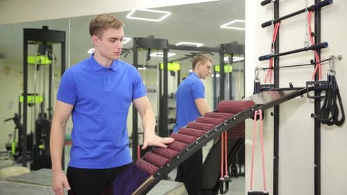 Young Man Demonstrates Rolling Massage Equipment in Gym