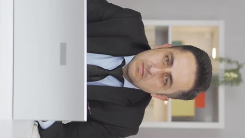 Vertical video of Home office worker man looking dull at camera.