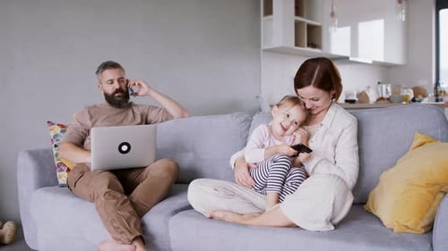 Family relaxing on couch with phone and laptop