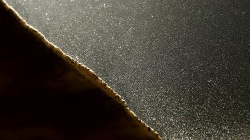 Kleine Sandkörner, die in abstrakter Makrozeitlupe den Hügel hinunterfallen