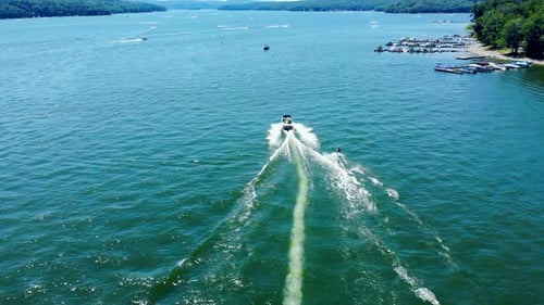 Birds eye view of tourists enjoying water skiing, tied behind high speed motor boat. Aerial.