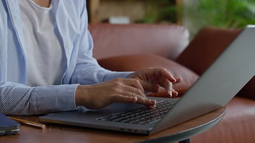 Woman Typing on Laptop at Table Indoors Daytime