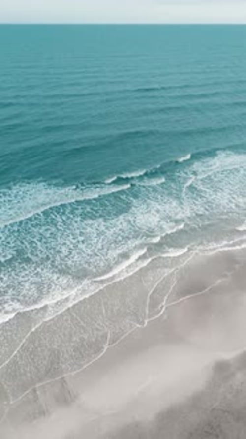 Vertical video of Drone aerial view of paradise beach. Turquoise sea water and clear sand at sunset.