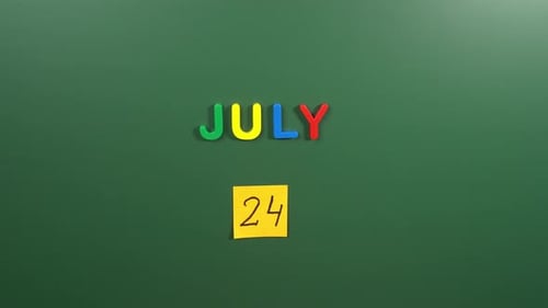 Hand sticking a sticker 24 July calendar day on school board. 24 date of July. Twenty fourth day
