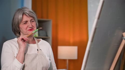 Senior Woman Thinking While Painting in Studio