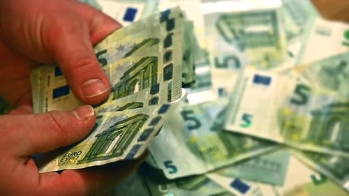 White male hands counting and flipping through stacks of 5 Euro bills, Tight shot