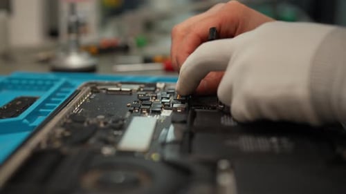Nahaufnahme eines Technikers, der die Komponente von der Laptop-Hauptplatine trennt, und zeigt, wie kompliziert das Gerät ist