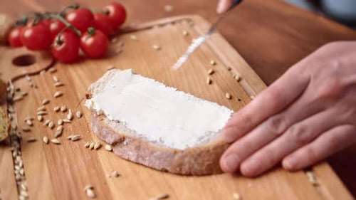 Person Spreading Cream Cheese on Bread Slice