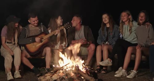 Friends Singing Around a Campfire at Night
