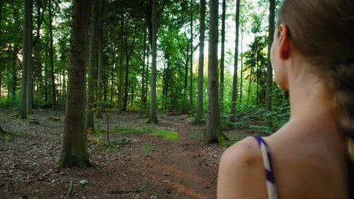 Close-up of a woman walking in dense forest, capturing a sense of wonder and connection with nature.