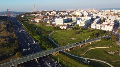 Drone shot tracking an urban train while it crosses a bridge right over a highway.