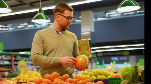 Man Selecting Grapefruits and Tangerines in Grocery Store