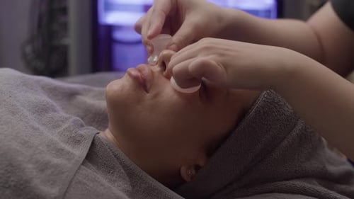 Frau lässt sich in der Klinik mit verjüngenden Quarzsteinen im Gesicht massieren