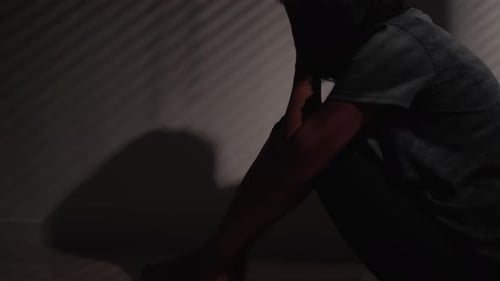 Woman Huddled in Corner in Dark Room